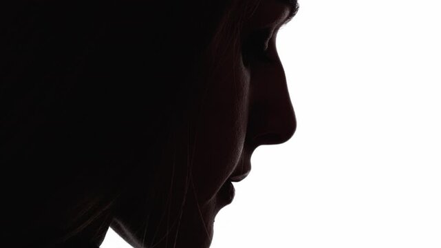 Upset face. Female silhouette. Disappointment loneliness. Dark contrast profile outline of sad depressed woman looking down isolated on white free space.