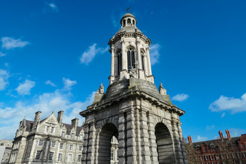 Obraz premium Iconic Trinity College Dublin, Ireland, featuring the iconic Campanile (bell tower). Tall, freestanding structure with a large arch at its base and an ornate cupola at the top. Multi-story structure