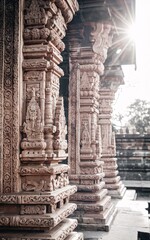 Intricate stone carvings on ancient temple pillars, sunlit. (1)