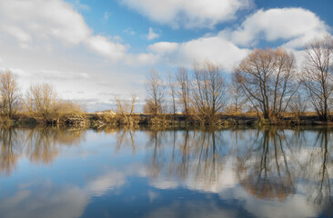 clouds running across the blue sky over the autumn river