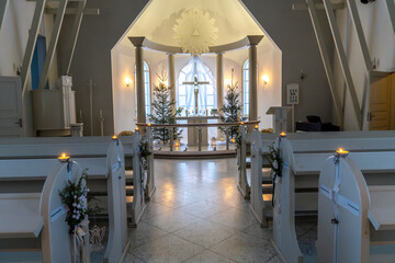 Beautifully Decorated Church Interior at Christmas. White Church Altar with Festive Candlelight and Trees.