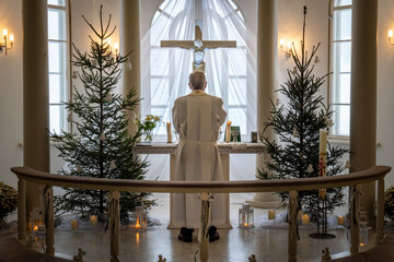 Priest Standing Before the Altar in a Festive Church. Clergyman in Christmas-Adorned Chapel.