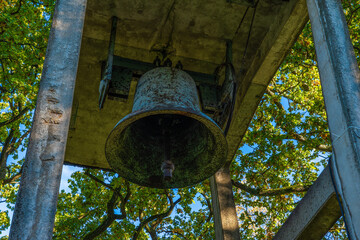 large bell surrounded by green foliage in a natural setting