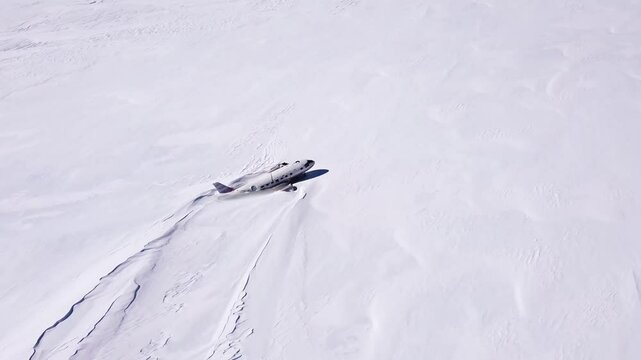 Abandoned plane covered in snow. Wreckage of the plane left in Antarctica. Ecological disaster. Pollution of the Earth. Aerial shot.