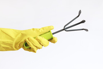 Small hand garden rake in a female hand on a light background. Gardener with a small rake,...