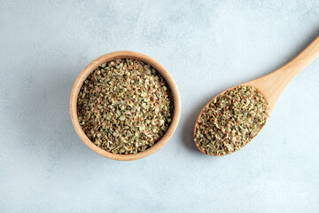 A bowl full of dried and ground natural mountain thyme on light background.