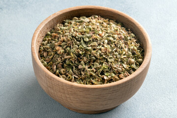 A bowl full of dried and ground natural mountain thyme on light background.