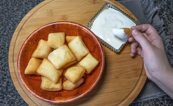 A woman's hand dips boorsok (baursak) into sour cream (kaymak) - this is the national food of the peoples of Central Asia.