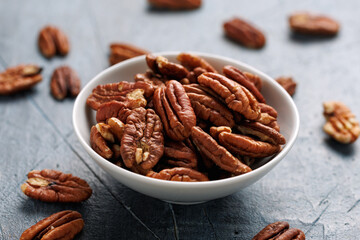 Pecan nuts in a white bowl on a rustic table