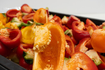 Top view of vibrant red, orange, and yellow bell peppers in a roasting tray lined with foil, seasoned and ready for baking. healthy meal preparation and cooking.healthy eating