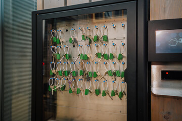 Key management system with multiple keys attached to green tags in a secure glass cabinet,...