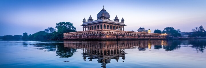 Fototapeta premium Serene dawn reflection of an ornate temple on calm water.