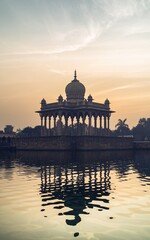 Obraz premium Sunrise over tranquil water reflecting ornate pavilion.