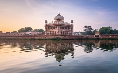 Fototapeta premium Sunrise reflection of a historical building on calm water.