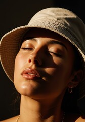 A person wearing a light-colored bucket hat, casting a shadow over their face, with a calm and contemplative expression.

