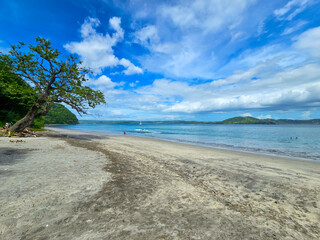 Blanca Beach and the blue waters of Culebra Bay, lush green trees, blue sky and clouds in Liberia Guanacaste Costa Rica