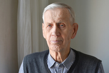 Portrait of a handsome old man 85 years old. A gray-haired elderly man wearing a shirt.