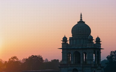 Obraz premium Sunrise silhouette of an ornate stone dome structure.