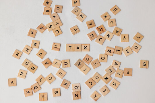 Wooden letter tiles spelling 'TAX' on a white background.