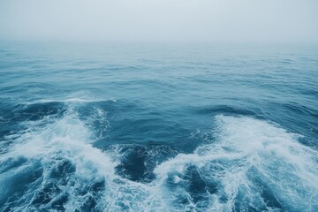 Waves crashing against each other in a tranquil blue ocean on a foggy day