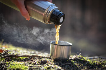 Kaffee eingießen aus Thermoskanne in Deckeltasse in der Natur