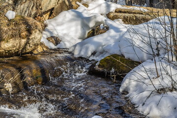 A fast river with rocky shores and snow in spring