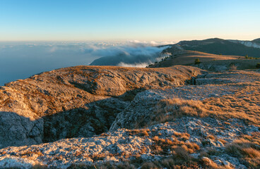 A mountain crevice illuminated by the evening sun located above the clouds