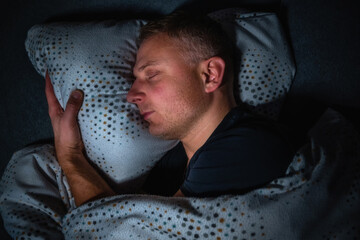 Mann schläft glücklich und zufrieden auf der Seite in einem kuschligen Bett