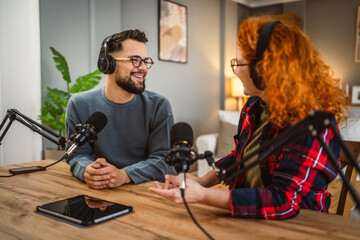 two presenters smile and enjoy while record podcast in home studio