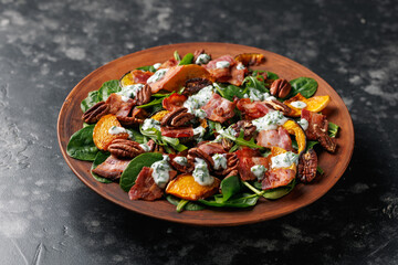 Baked pumpkin bacon salad with spinach and pecan nuts. Healthy food.