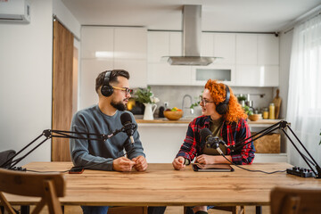 two presenters smile and enjoy while record podcast in home studio