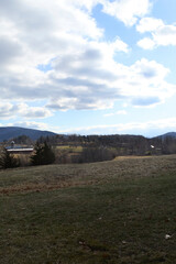 A winter landscape with a rolling field and forest in the background. 