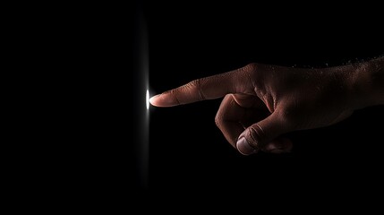 Fingertip touching glowing light in dark.