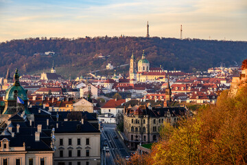 Obraz premium Sunrise casts a warm glow over the historic buildings of Lesser Town, Prague. The peaceful streets and rooftops are accented by the looming hills, creating a serene morning atmosphere.