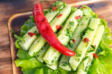 Fresh salad with cucumber, herbs, and chili on a wooden cutting board