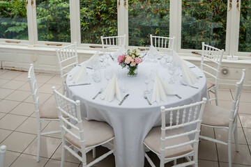 White stylish decorated restaurant interior with natural lighting for minimalist wedding celebration near the garden, no people, empty