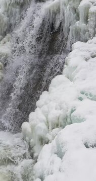 Vertical close up of a icy waterfall, river, flowing with snow and ice along each side 29.97 FPS Frames / Second,	Iphone 16 Pro