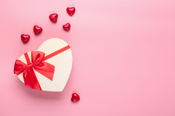 Valentine's Day celebration. Heart-shaped gift with little decorative hearts on pastel pink background. Free space for your text