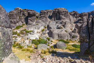 A carved image within a rock face, accessed by stone steps, creates a sense of sacred space and history against a clear blue sky