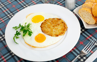 On plate are vegetable pancakes made from grated zucchini cooked with fried eggs sunny-side up eggs