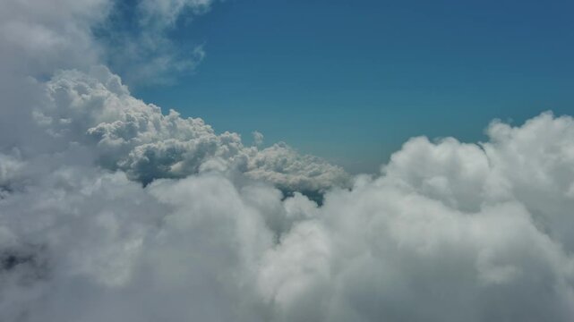 Flying through beautiful white fluffy clouds in blue sky. Airplane travel background, 4k