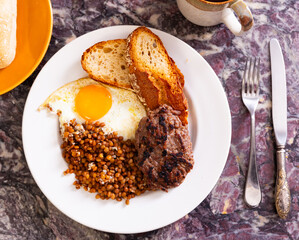 Appetizing roasted beef hamburger cutlet served with lentils and fried egg on platter