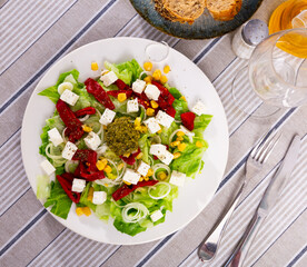 Appetizing salad of fresh vegetables served with feta cheese and pesto on plate