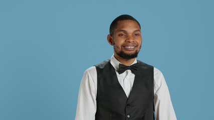 Portrait of bellhop hotel employee posing with arms crossed, showing confidence and professionalism dressed in a tuxedo and tie. Doorkeeper bellboy works in hospitality industry. Camera A.
