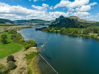Aerial view of a Waikato River with a containment boom. Environmental cleanup in progress. Protecting the waterway. WHAKAMARU-AOTEA, WHAKAMARU, WAIKATO, NEW ZEALAND