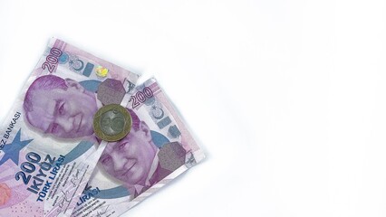Two 200 Turkish lira banknotes and a 5 lira coin placed on a clean white background. The image provides ample copy space, ideal for financial or economic themes.