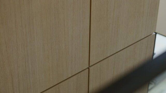 Close up view of wooden cabinet or set of drawers. Wood has light natural finish and panels aligned with visible seams