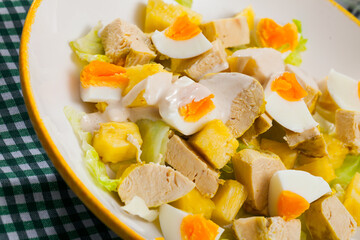 Piquant salad of chicken fillet, canned pineapple, fresh lettuce and eggs served on white plate..
