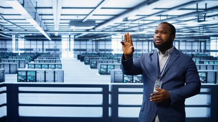 System administrator looking at holograms in data center, monitoring equipment. Employee in server...