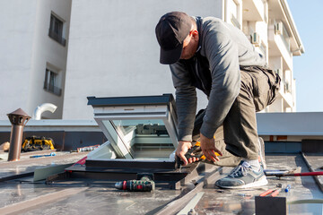 Fototapeta premium A roofer builder worker finishing folding a metal sheet using special pliers with a large flat grip. A roofer and window master work.